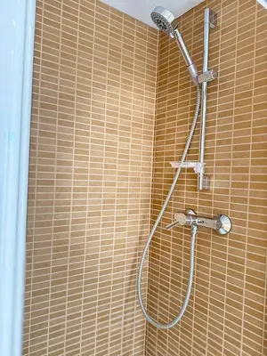 a shower in a bathroom with a brown tiled wall at Boutique Temporada VG Barcelona Sant Gervasi in Barcelona