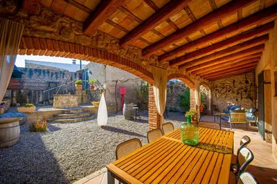 an outdoor patio with a wooden table and chairs at La Masia in Sant Pau dʼOrdal