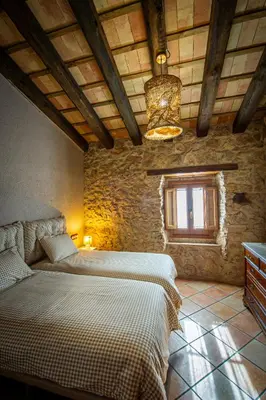 a bedroom with two beds in a stone wall at La Masia in Sant Pau dʼOrdal
