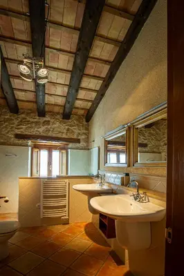 a large bathroom with two sinks and a toilet at La Masia in Sant Pau dʼOrdal
