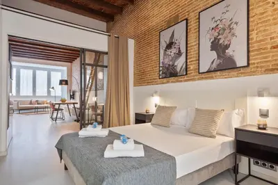 a bedroom with a large bed and a living room at Alcam Gracia in Barcelona