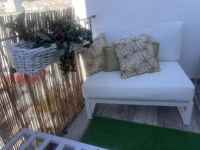a white couch on a balcony with a green rug at Atico 1º linea vistas Sitges in Sitges