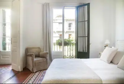 a bedroom with a bed and a chair and a window at Céntrico y espacioso apartamento in Barcelona