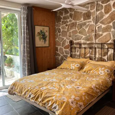 a bed in a room with a stone wall at Estudio limonero en Sant Cebriá de Vallalta 20' playa in Sant Cebrià de Vallalta