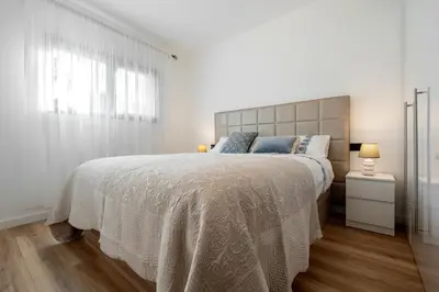 a white bedroom with a large bed and a window at Hauzify I Casa Somella in Vilanova i la Geltrú