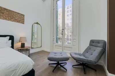 a bedroom with two chairs and a bed and a window at Precioso apartamento en Rambla Cataluña 35 in Barcelona