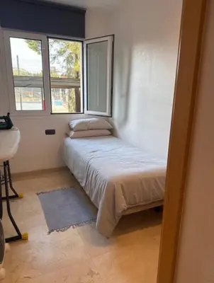 a small bed in a room with two windows at Surf&Snooze in Castelldefels