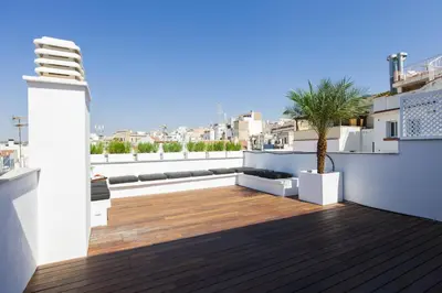 a rooftop deck with a palm tree on a building at Kare No Apartments by Sitges Group in Sitges