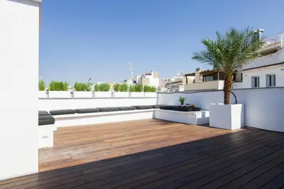 a rooftop deck with a palm tree on a building at Kare No Apartments by Sitges Group in Sitges
