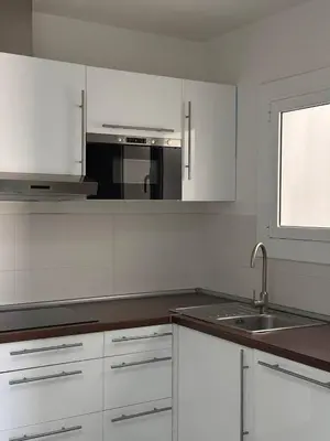 a kitchen with white cabinets and a sink and a window at City Center 3 Bedroom Apartment! in Barcelona