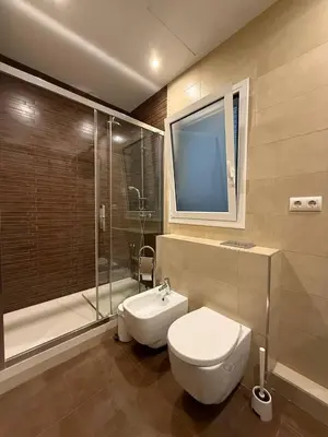 a bathroom with a toilet and a shower and a tv at Centric 2 Bedroom Apartment in Barcelona
