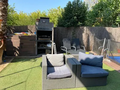 a patio with two chairs and a grill in a backyard at Apartamento 3 habitaciones con piscina in Sant Cugat del Vallès