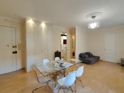a living room with a glass table and white chairs at Elegant apartment Rambla Badal in Barcelona