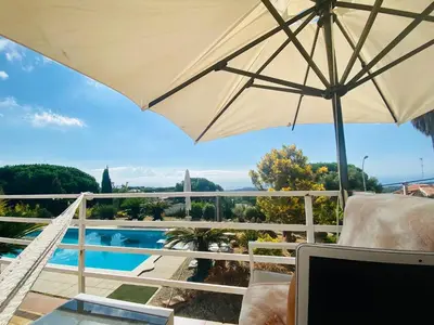a patio with an umbrella and a view of a pool at CAN FENICIA - 30 min to F1 & MotoGP - Intimate Villa, Private Pool & Sea View in Arenys de Munt