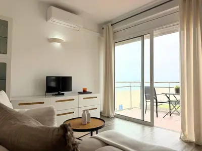 a living room with a couch and a tv and a balcony at Atico frente al mar! in Gavà