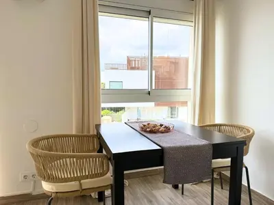 a dining room with a table and chairs and a window at Atico frente al mar! in Gavà