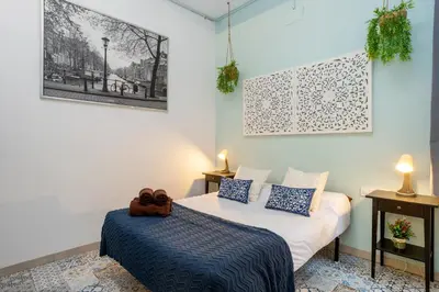 a bedroom with a bed with blue and white pillows at Estudios a 10' caminando de la playa y a 20' de Barcelona Centro in Sant Adria de Besos