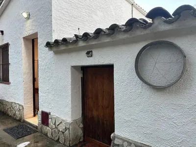 a white building with a wooden door and a round window at Vallromanes House of Peace and Rest in Vallromanas