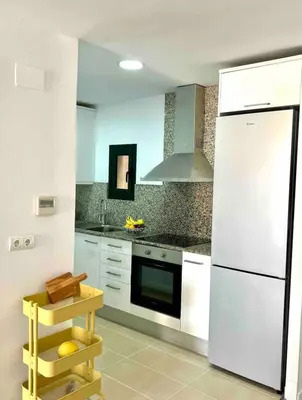 a kitchen with white appliances and a white refrigerator at Artistic beach apartment in Cunit