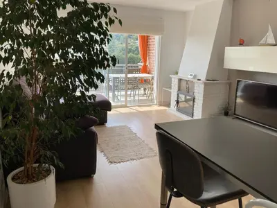 a living room with a table and a tree in it at Apartamento con vistas al mar in Castelldefels