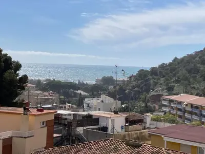 a view of the ocean from the roofs of buildings at Apartamento con vistas al mar in Castelldefels
