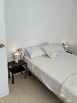 a bedroom with a bed and a side table with two lamps at Apartament a Arenys de Mar in Arenys de Mar