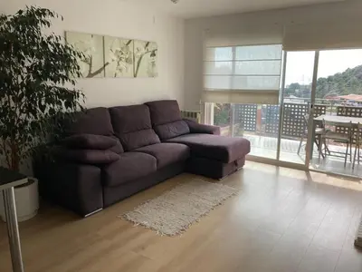 a living room with a brown couch and a table at Apartamento con vistas al mar in Castelldefels