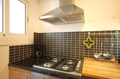 a black tiled kitchen with a stove and a window at Lets Holidays New Flat Beachfront In Castelldefels in Castelldefels