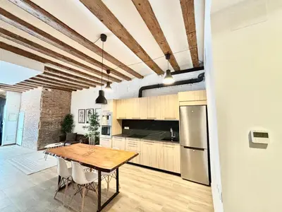 a kitchen with a wooden table and a refrigerator at Piso con dos habitaciones con camas dobles y terrazas en el Poblenou in Barcelona