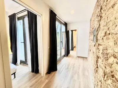 a room with large windows and a stone wall at Piso con dos habitaciones con camas dobles y terrazas en el Poblenou in Barcelona