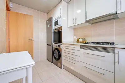 a kitchen with white cabinets and a washer and dryer at Hauzify I Casa Ribera in Cunit