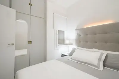 a white bedroom with a large bed with a large headboard at Nice, Cozy, UP TO 6, FCB stadium, free parking in Barcelona