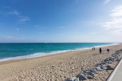 a group of people walking on the beach at HomeHolidaysRentals Olai - Costa Barcelona in Pineda de Mar