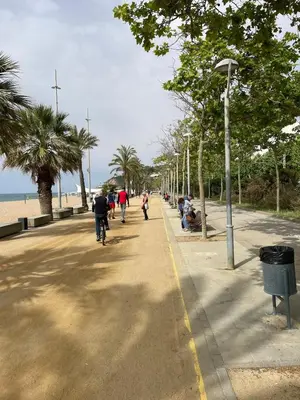 a group of people walking down a sidewalk near the beach at Flat with birdsongs & character! in Calella