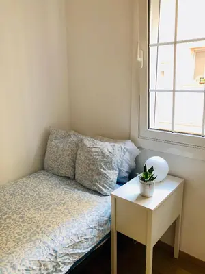 a small bedroom with a bed and a table at Habitación privada junto al mar en la Barceloneta in Barcelona
