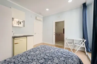 a small bedroom with a bed and a kitchen at Habitación 1 NOU DE LA RAMBLA in Barcelona