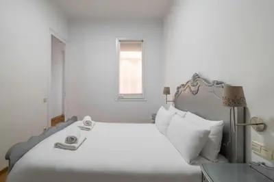 a white bedroom with a large bed and a window at Stay U-nique Apartment Creu Coberta II in Barcelona