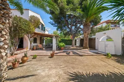 a backyard with a white garage and palm trees at Casa Alba Garden & Calm in Sitges