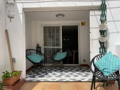 a porch with three chairs and a rug at Apartamento con jardín cerca playa y a 15 min de Plaza Catalunya en tren in Sant Adria de Besos