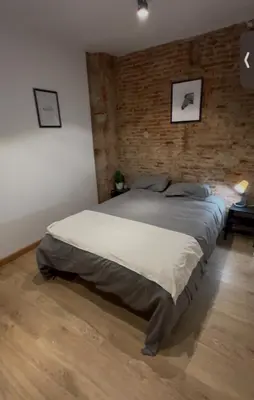 a bedroom with a large bed with a brick wall at Ink House in Barcelona