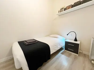 a white bedroom with a bed and a night stand at Bogatell Playa Apartment in Barcelona