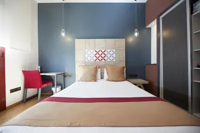 a bedroom with a large bed and a red chair at Boutique Hostemplo Sagrada Familia in Barcelona