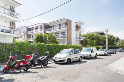 a row of cars and scooters parked on a street at Stay U-nique Apartments Sitges Beach in Sitges