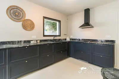 a kitchen with black cabinets and stools in a room at Villa Caliza in Cunit with Private Pool and large garden - air conditioning in bedroom in Cunit