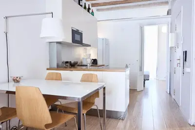 a white kitchen with a table and chairs at Sunny apartment on the square in Barcelona