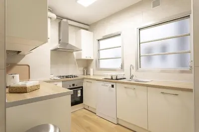 a white kitchen with white cabinets and a sink at Gran Vía Suites in Barcelona