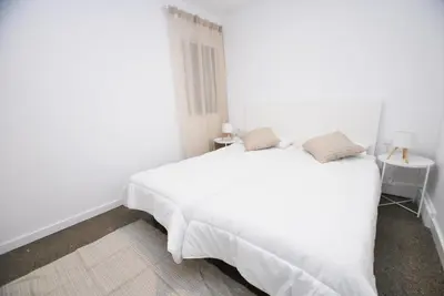a white bedroom with a white bed and a table at Premia Palm View in Premiá de Mar