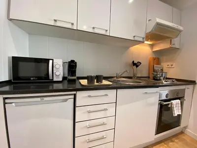 a white kitchen with a microwave and a sink at PISO FILIPPO in Barcelona