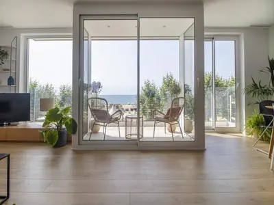 a living room with glass doors with chairs and a table at Seafront Apartment in Calella with Beach Access in Calella