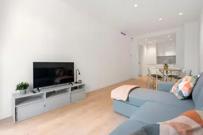 a living room with a blue couch and a tv at Monthly 32 Nights 1BR Pools Parking in Barcelona